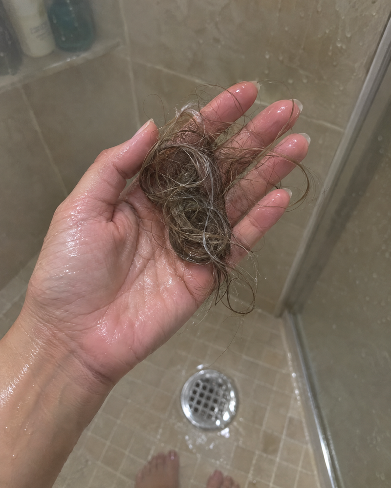 Holding a clump of shed hair pulled from the shower drain