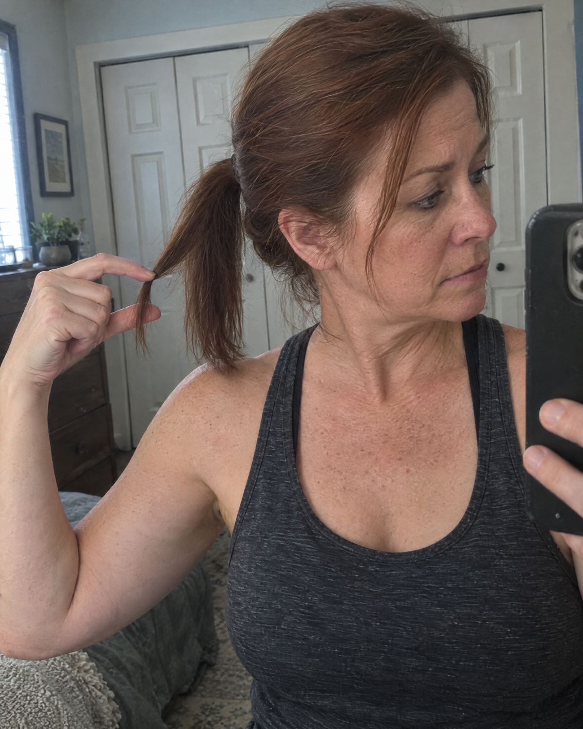 Woman gauging the thickness of her ponytail in a mirror