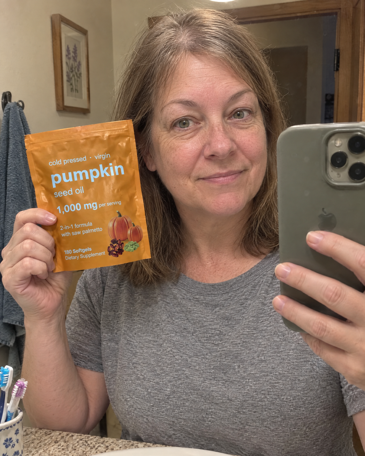 Woman in her fifties holding the pouch in a bathroom mirror selfie